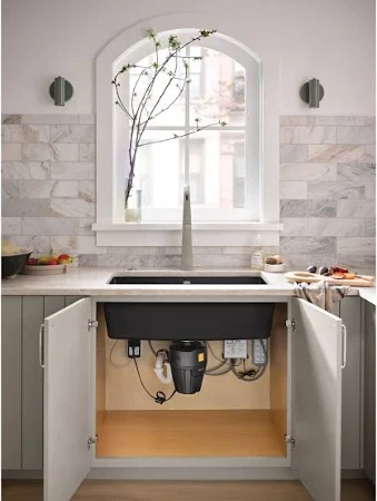A person using a garbage disposal in a kitchen sink.